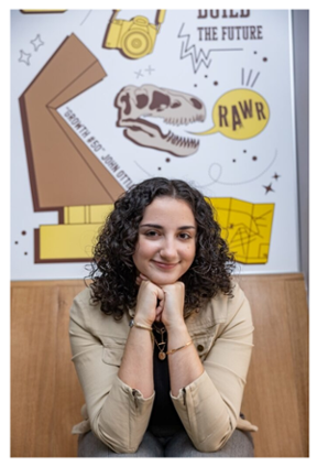 Image of Julianna Menna in front of her collage-style mural with #RowanProud images