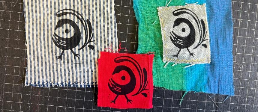 Three pieces of brightly colored scrap fabric with a print of a bird stamped on each one.