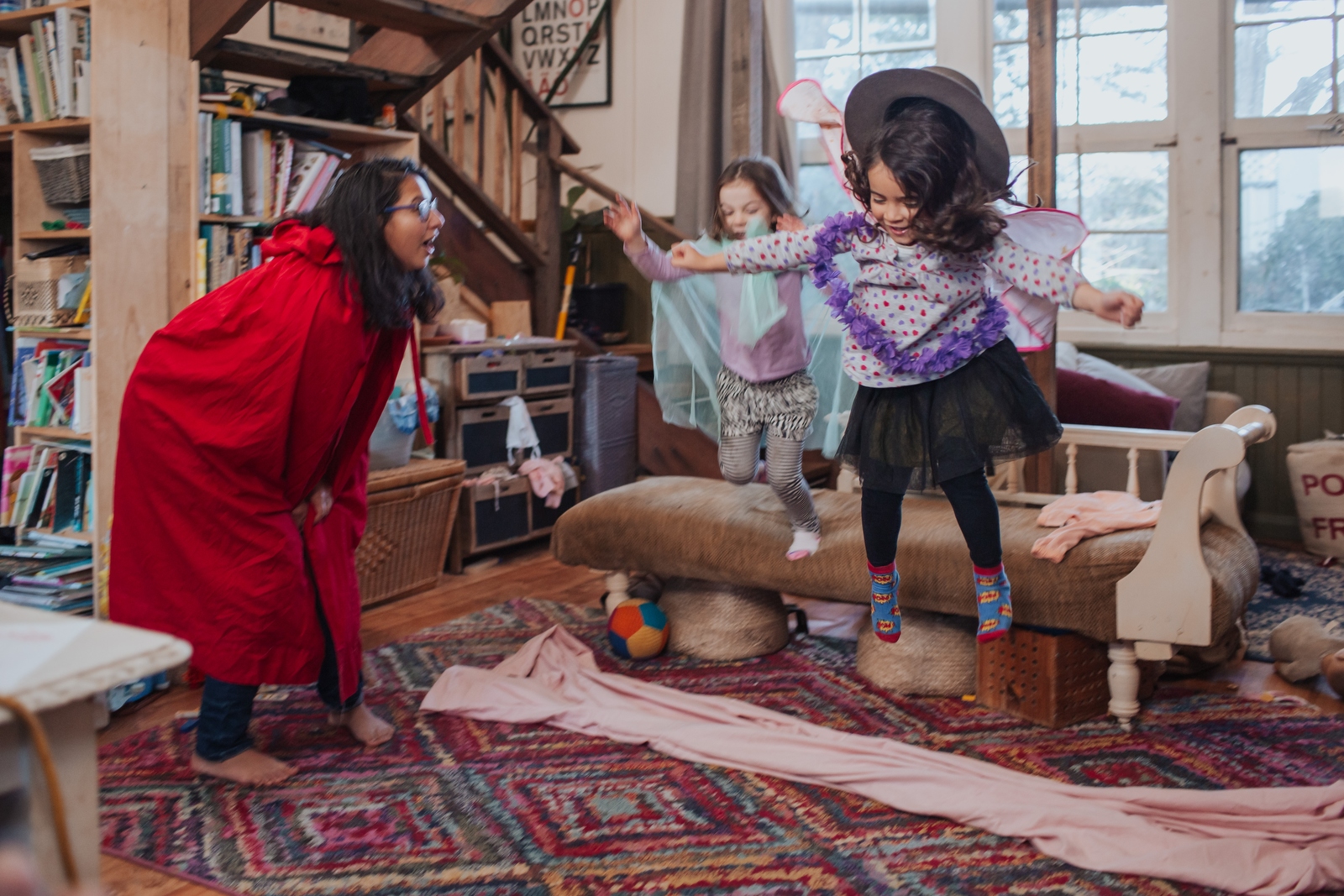 A mom and two kids dressed up  and playing in a messy living room