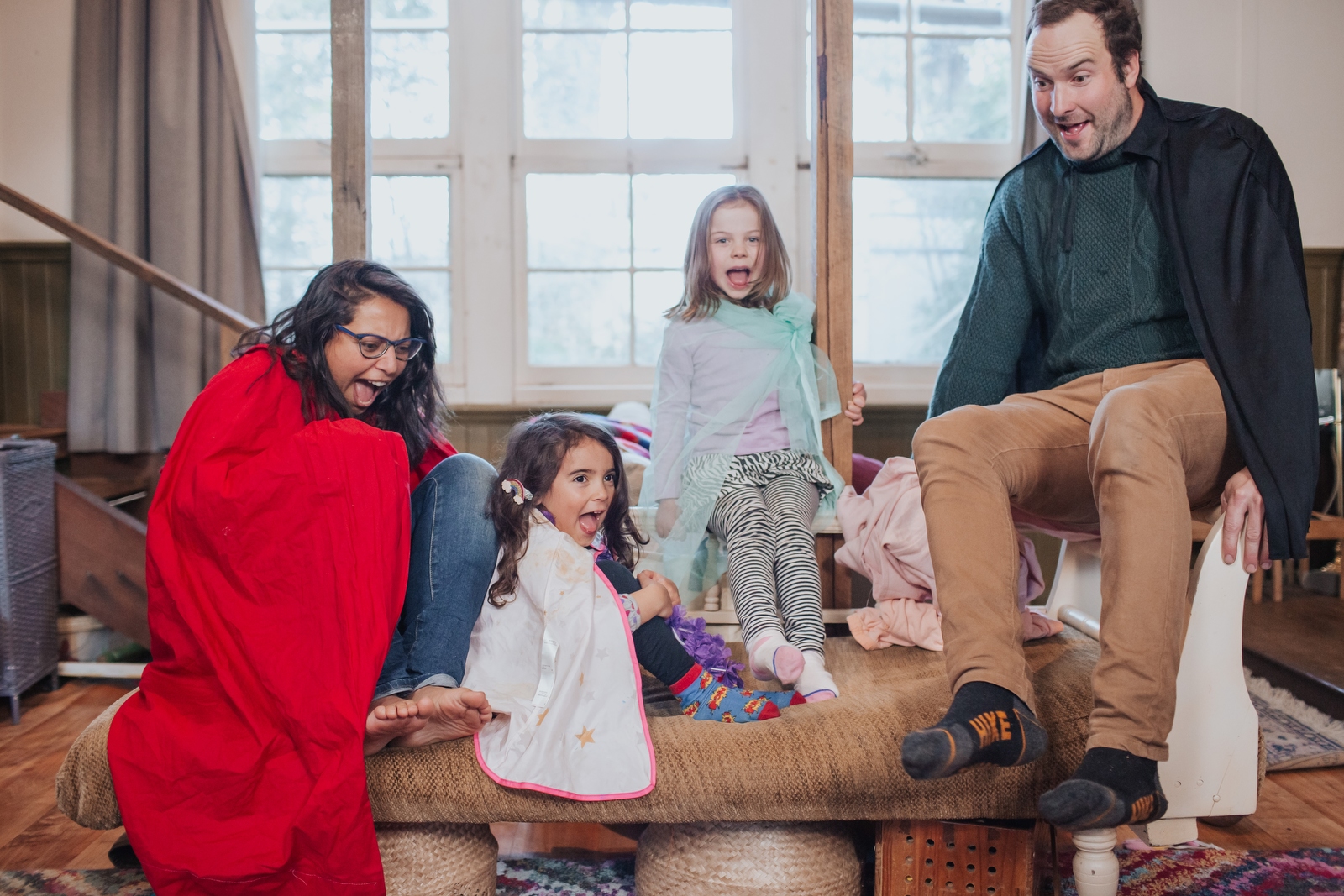 A family with two grown ups and two kidsplaying floor is lava in their living room