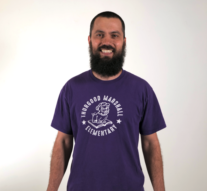 Bejamen Prager i wearing a purple shirt and smiling at the camera.