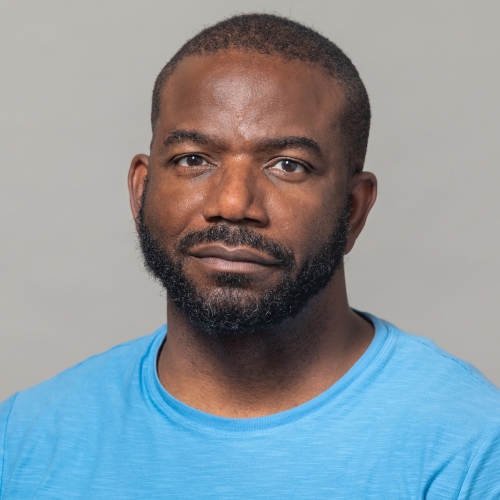 Kehinde Bademosi wearing a blue shirt and smiling at the camera.