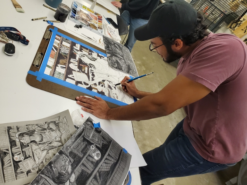 Click to learn more about the department of art, there is an image of a student sketching on a table in the art lab