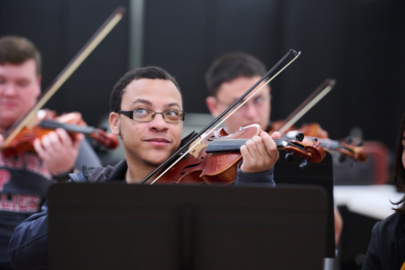 Click to learn more about the Department of Music, there is a student with glasses in violin class