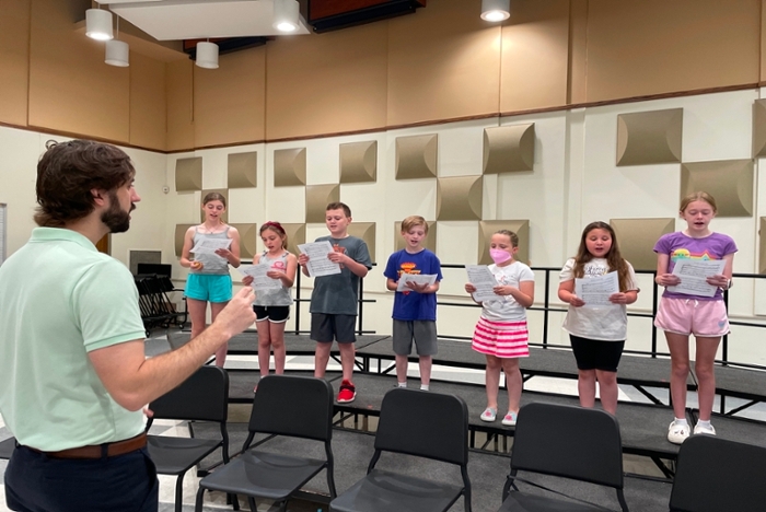 7 youth choir students on riser in choir room with instructor