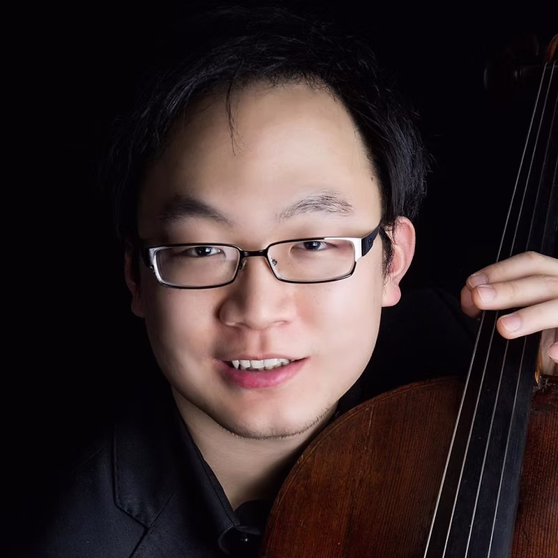 Closeup headshot of a young Asian man with glasses holding his cello
