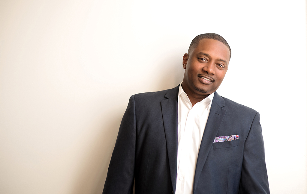 michael mcarthur in a white shirt and blue blazer smiling