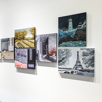 Student artwork hanging on a white wall.