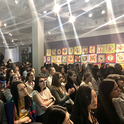 A group of people are sitting in a gallery space.