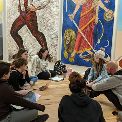 Students and a professor are seated inside The Sister Chapel installation.