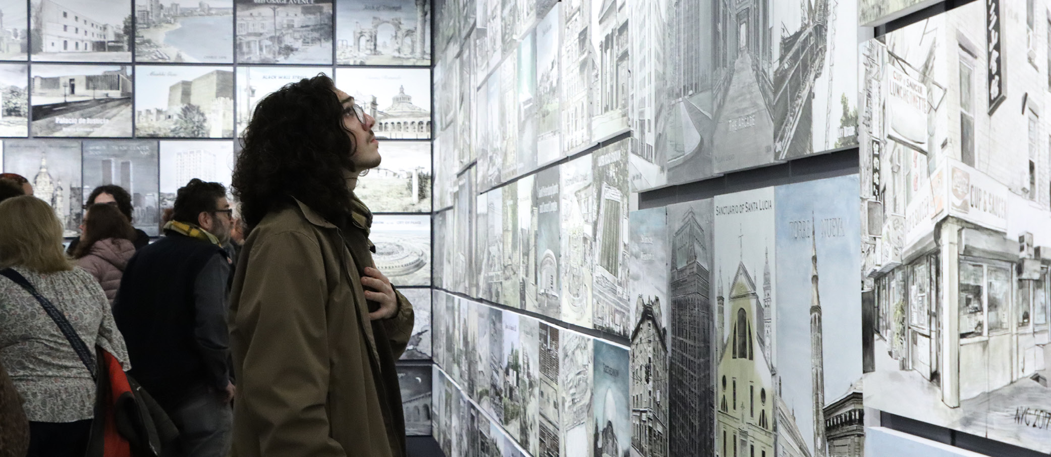 Visitor viewing multiple paintings on the wall.