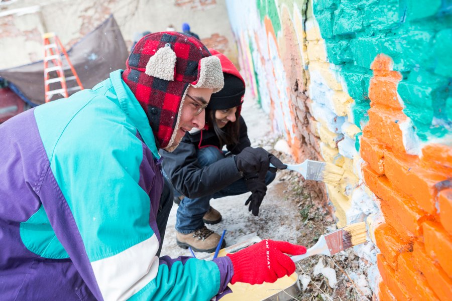 A photo of CMSRU students working on a service learning activity, which is painting an outdoor mural.