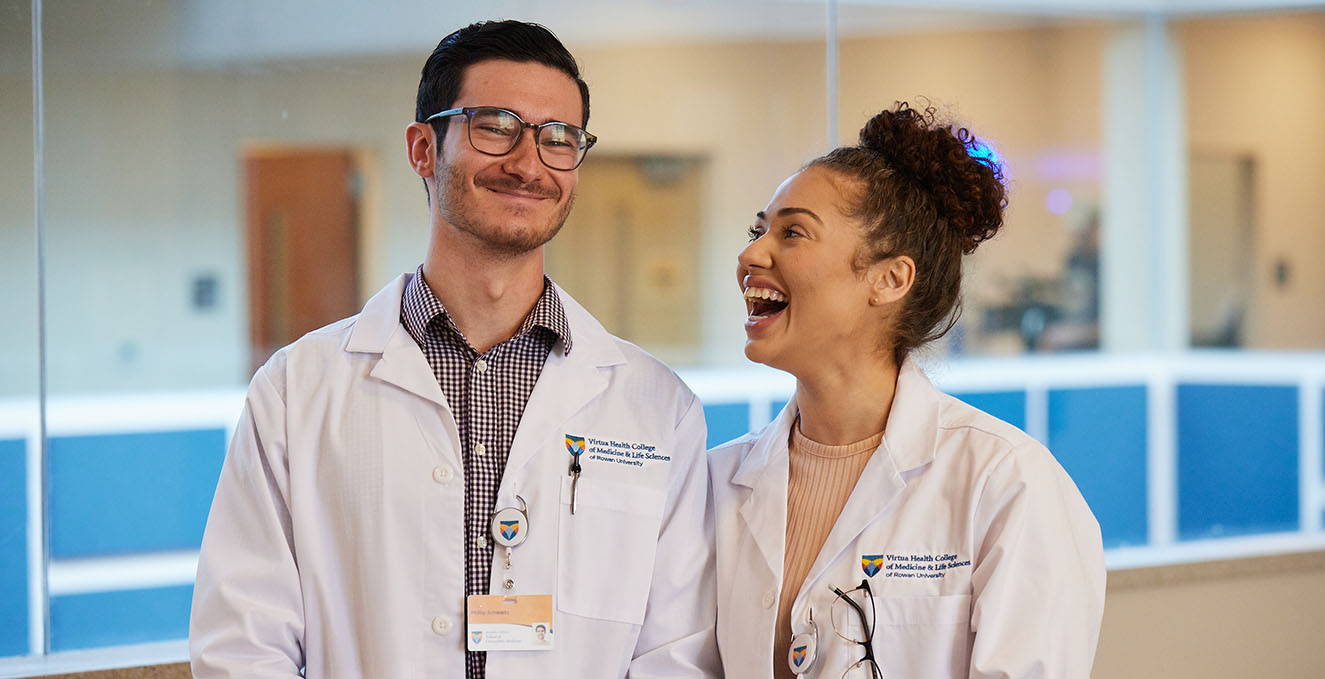 A close up of two doctoral students laughing.