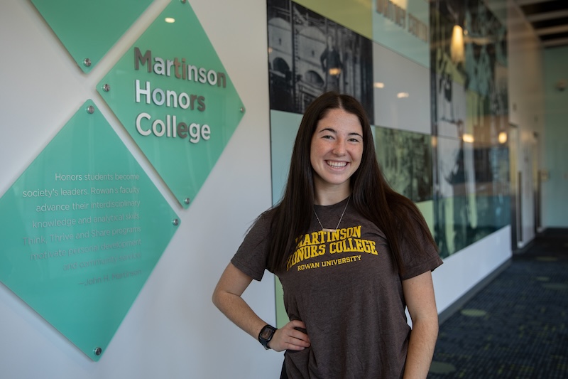 A student smiles wearing a John H. Martinson Honors College shirt.