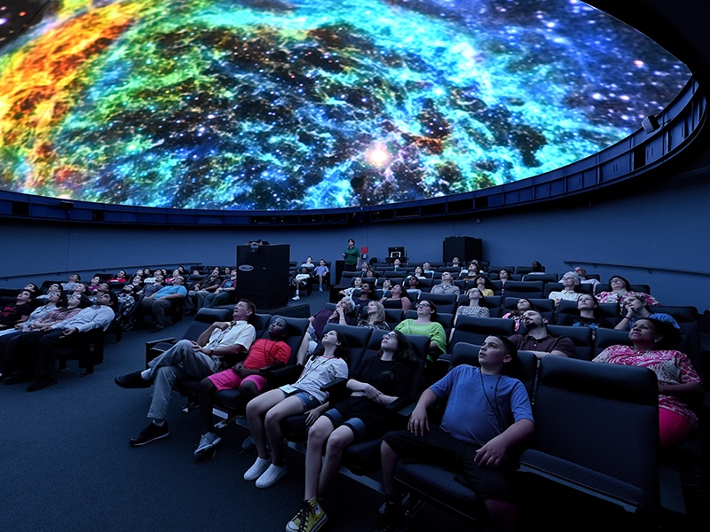 A group of young students sitting in the planetarium watching a show.