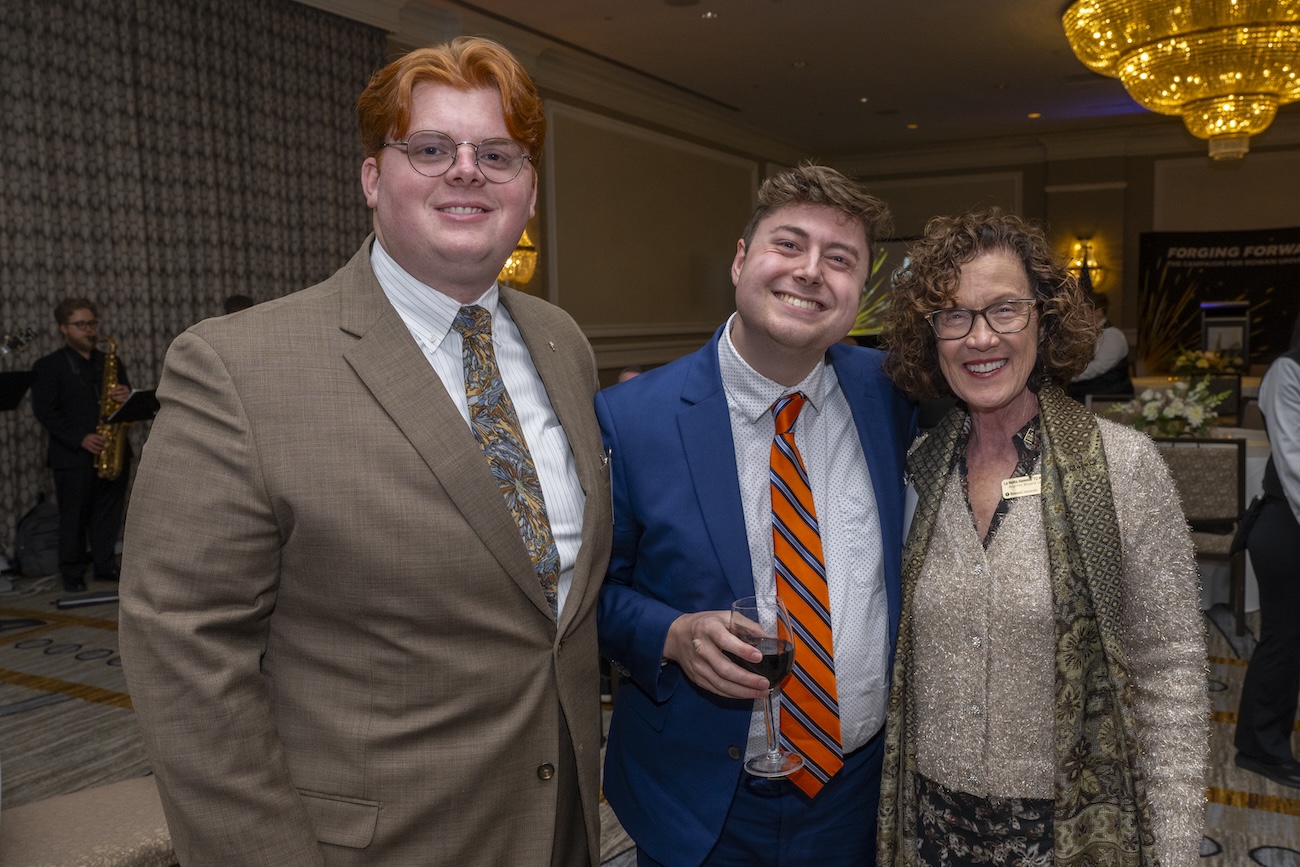 A group photo of three students at an event.