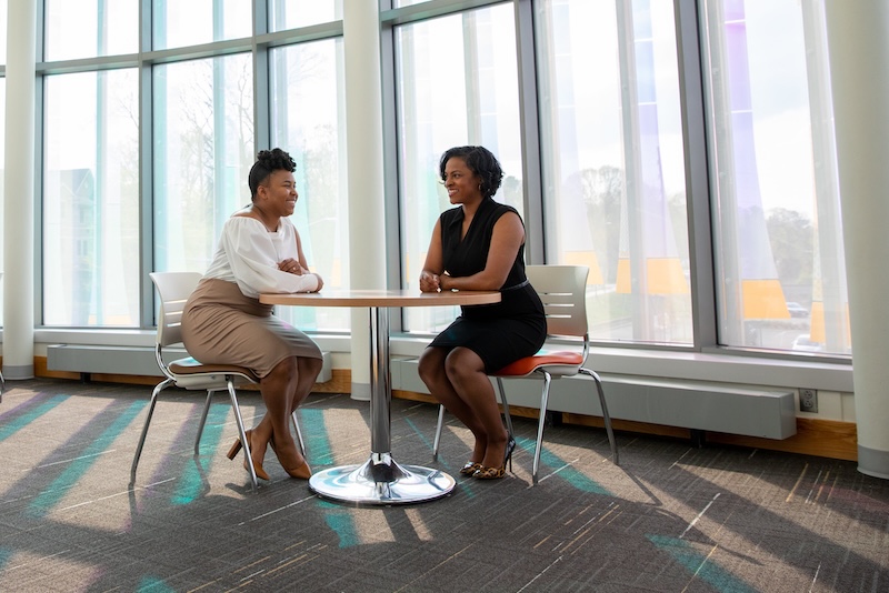 Two adult learners chat in the College of Business.