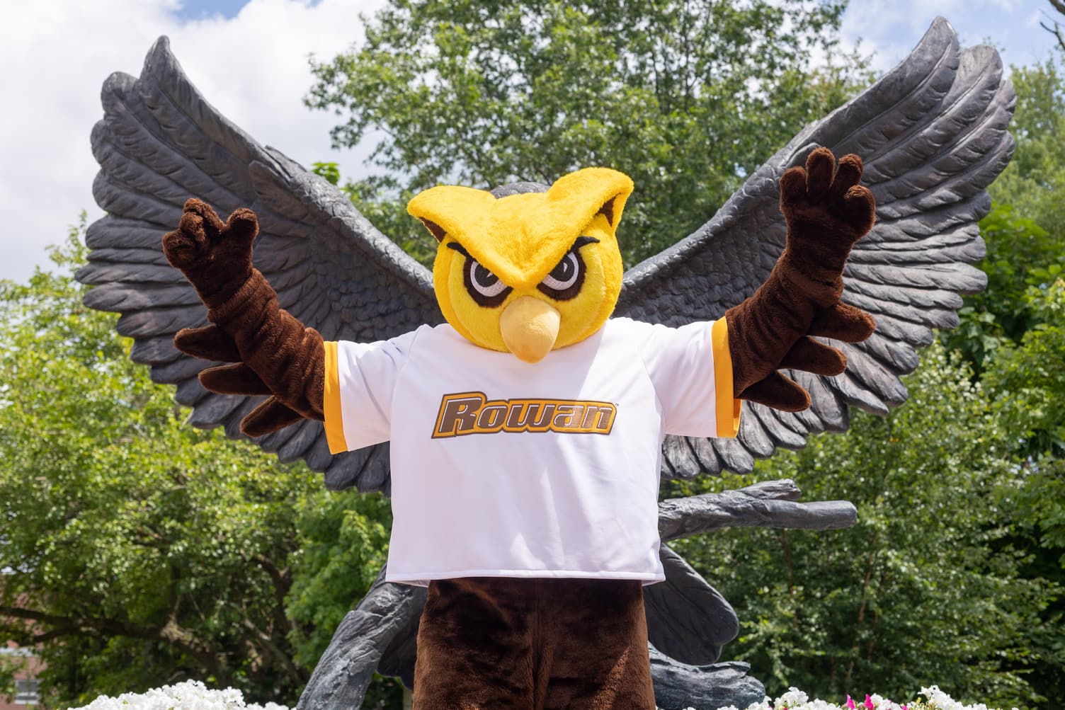 prof mascot standing in front of owl statue