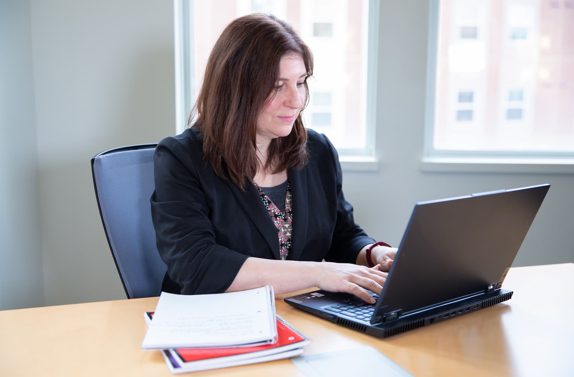An adult student sits at a desk while working on a laptop.