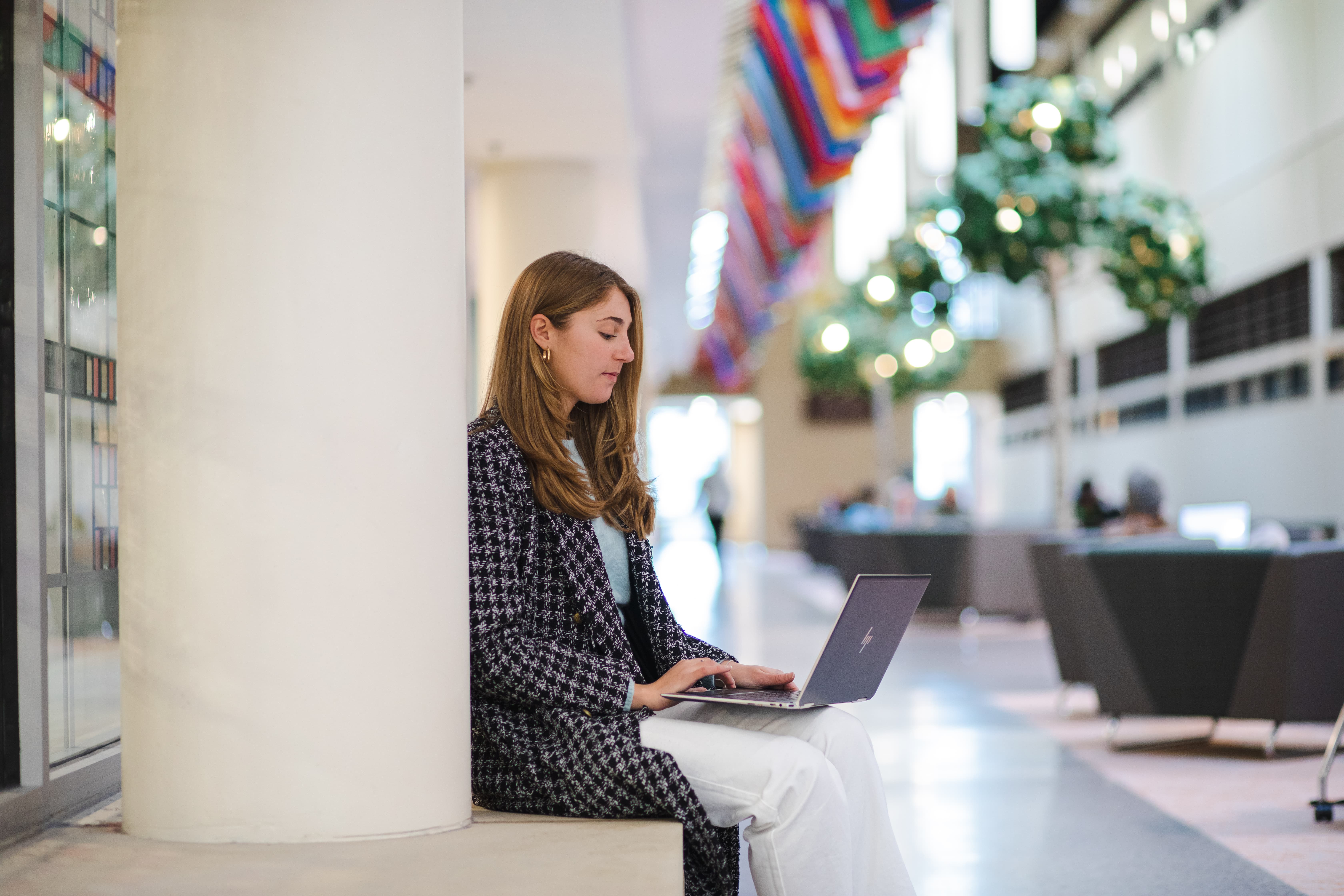 A Rowan student sits at a table while working on their laptop on Rowan's main campus in Glassboro, NJ. 
