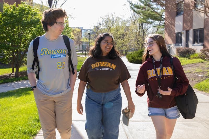 Three Rowan students walk and talk together on Rowan's main campus in Glassboro, NJ.