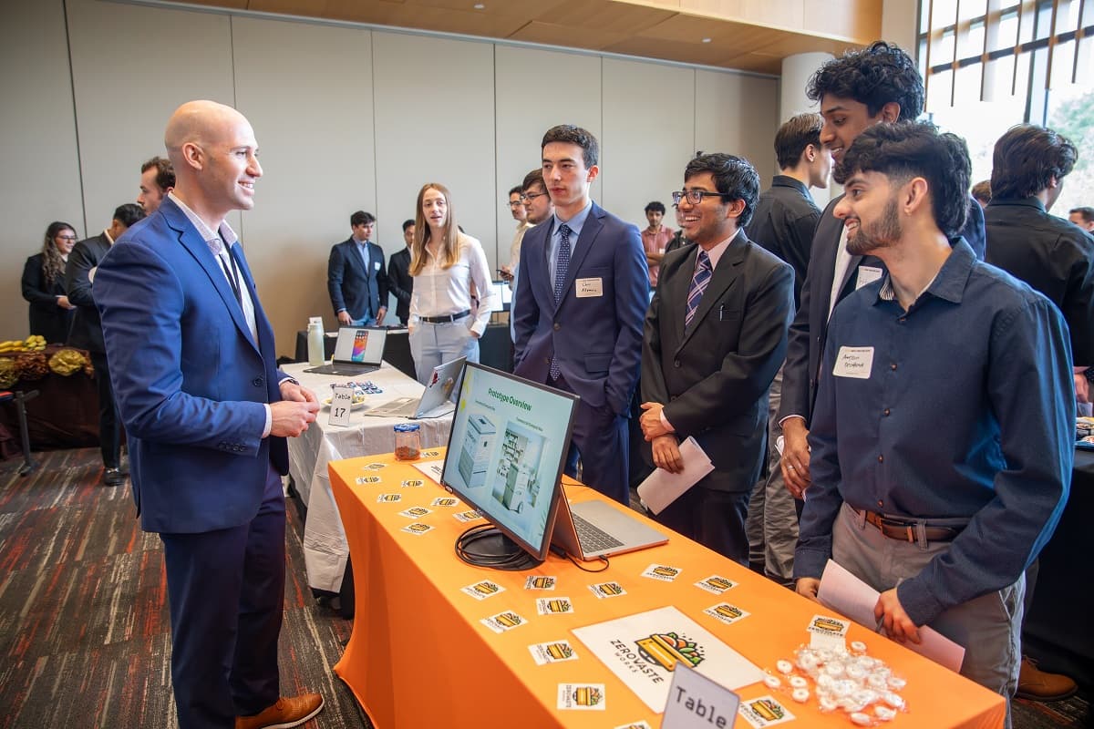 4 business at a convention booth smile and chat with a company rep