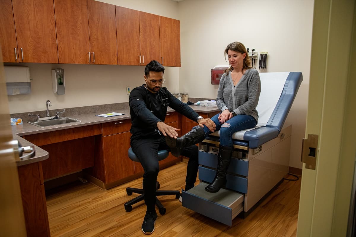 a male nurse in a chair examines a patient's leg