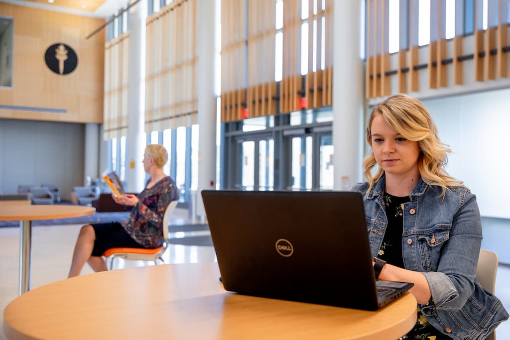 woman-works-on-a-laptop-at-table-in-lobby