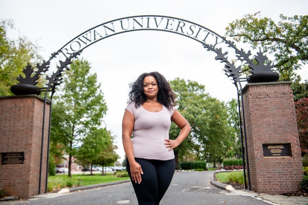 A student poses for a photo under the Rowan University arch on Rowan's main campus in Glassboro, NJ.