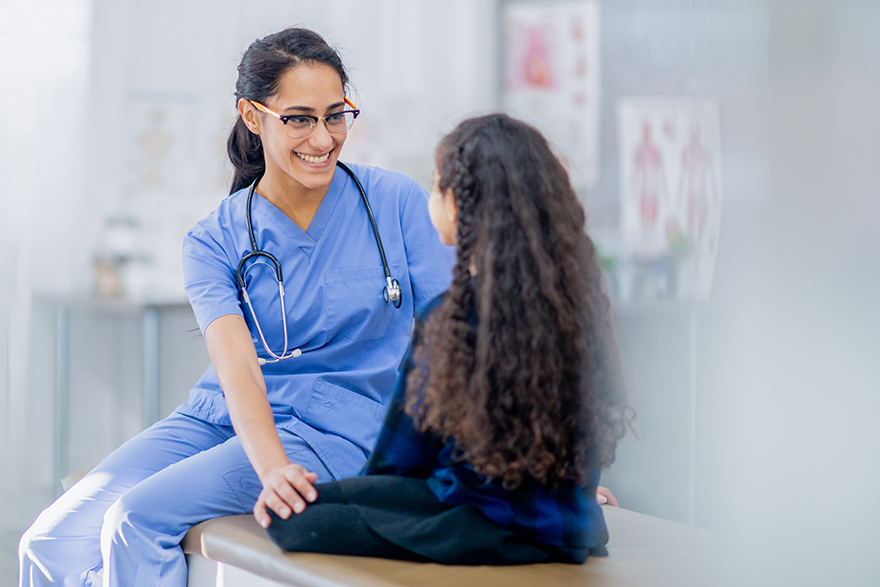 A healthcare professional smiles while sitting and talking to a patient. 