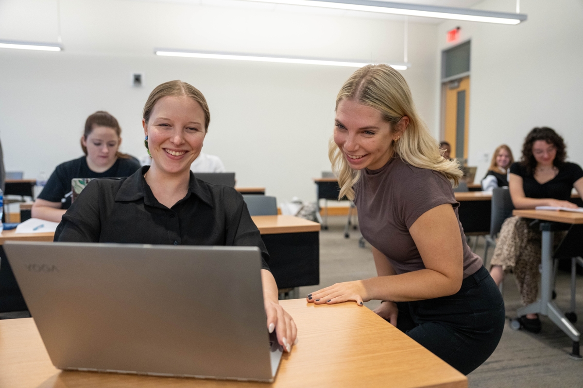 A student helps another student on the computer.