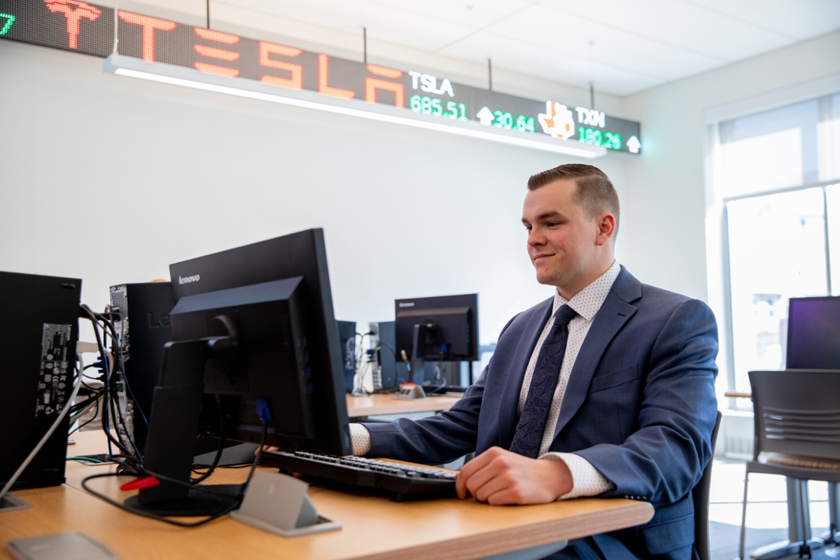 A Rowan student smiles while looking at their computer in a classroom in the Rohrer College of Business on Rowan's main campus in Glassboro, NJ.