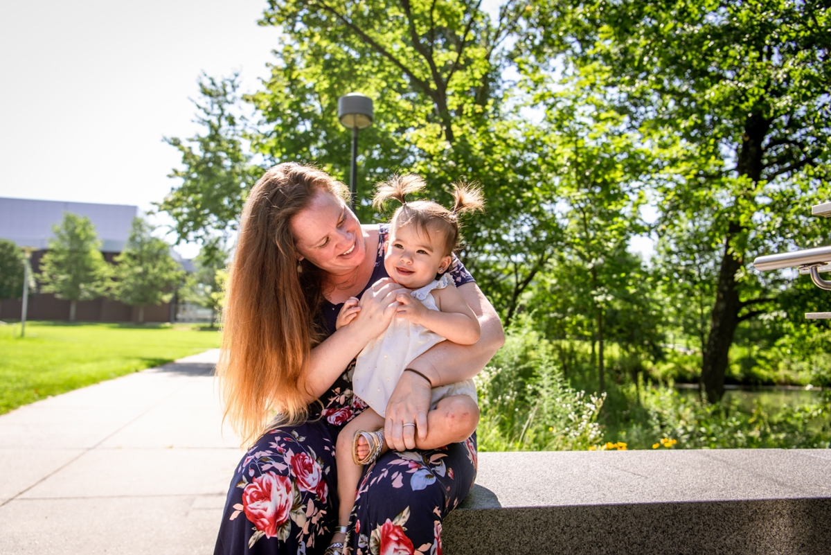 A woman smiles while holding a child.