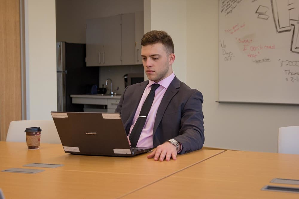 A business student at a table working on his computer