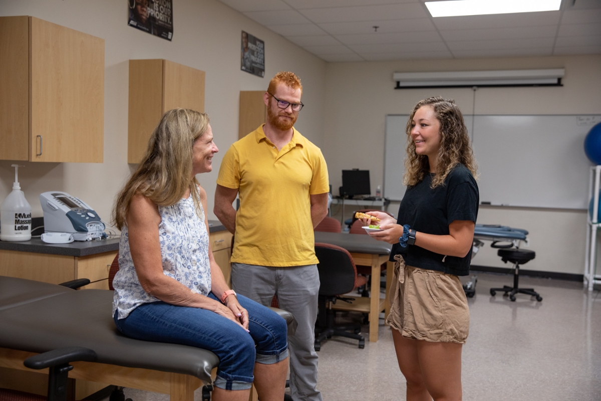 Three individuals smile and talk.