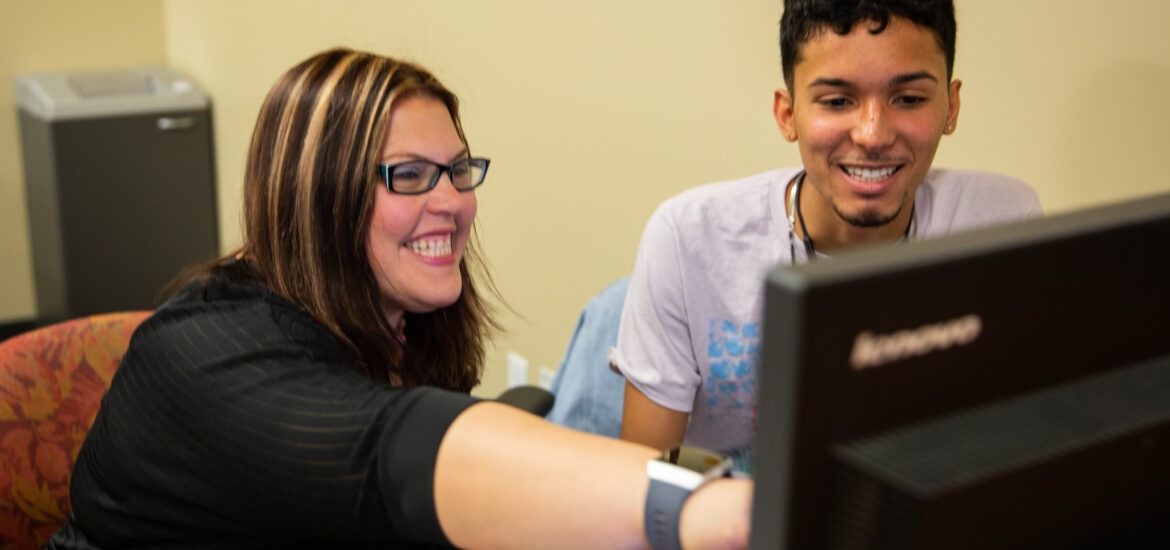 A student and professor work together at a computer.
