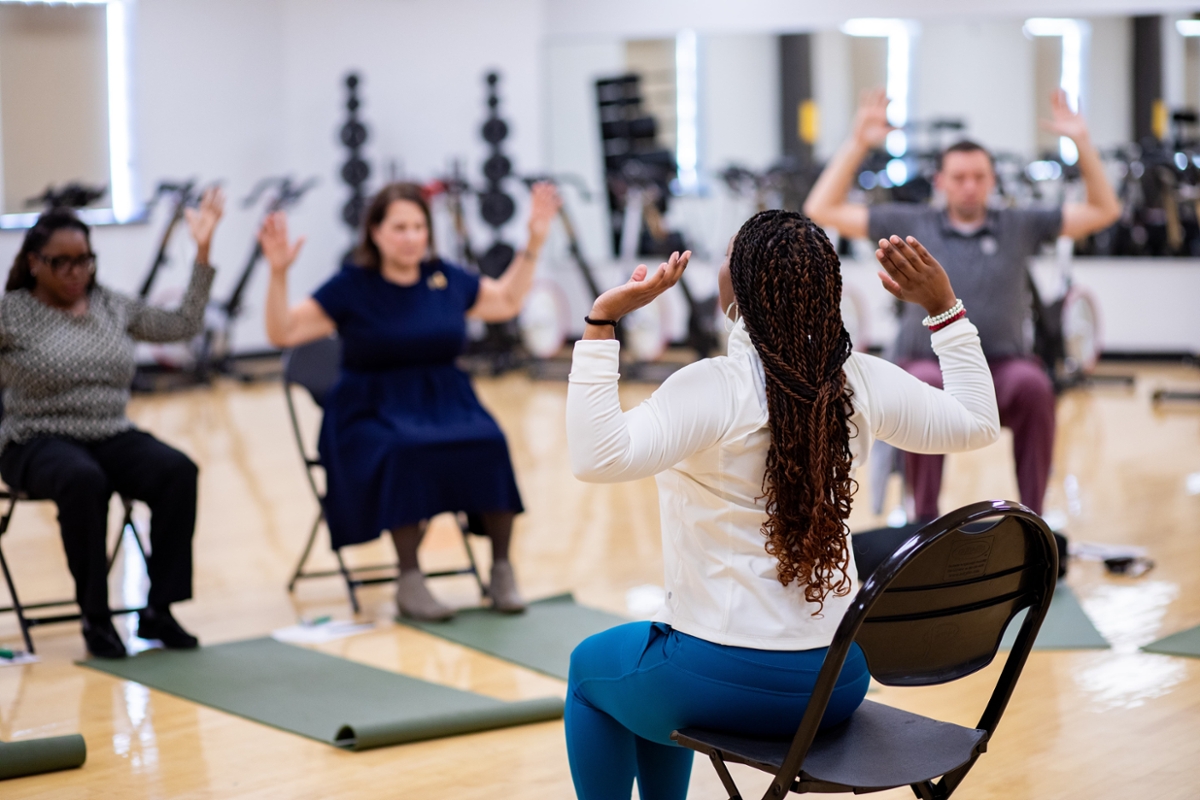 A group in a chair yoga class in a group fitness room.