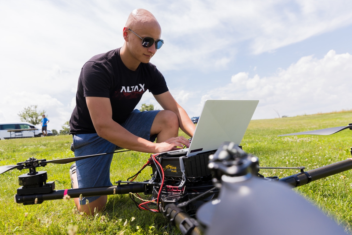 A student works on their laptop out in a field.