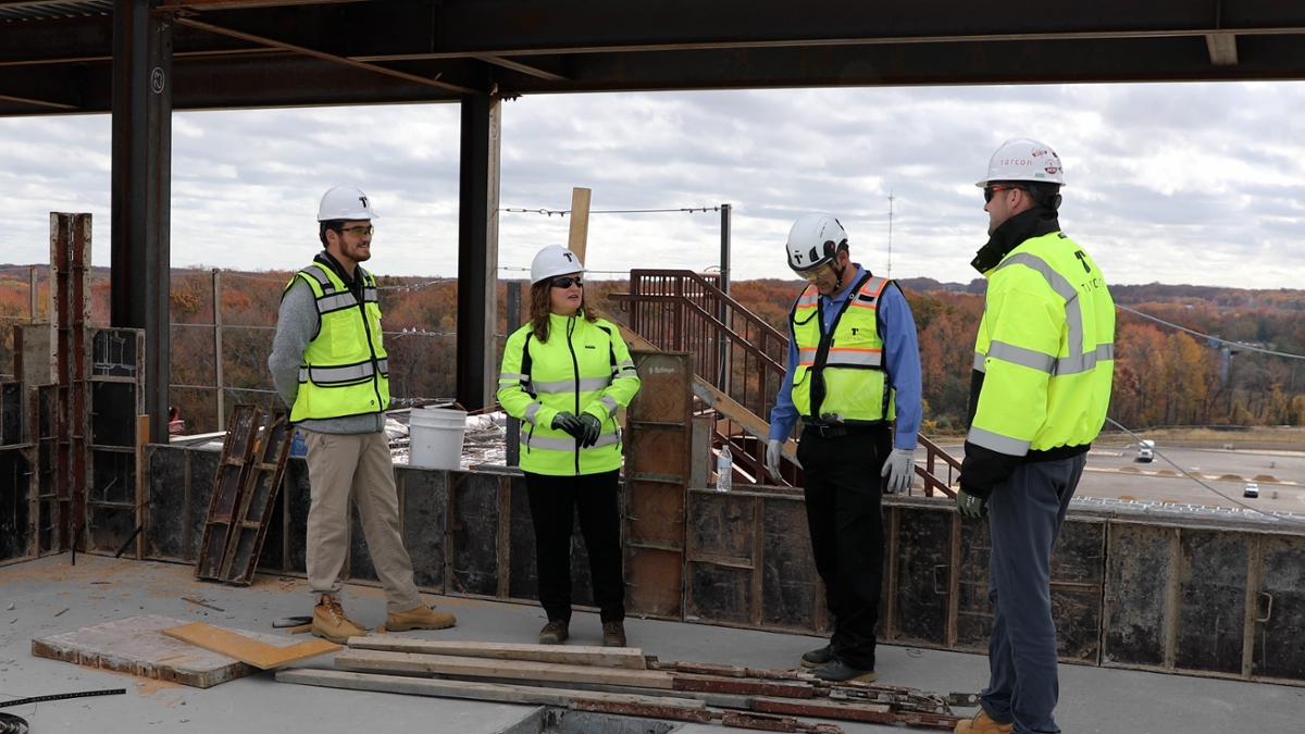 A construction crew meets together and discusses something at a construction site. 