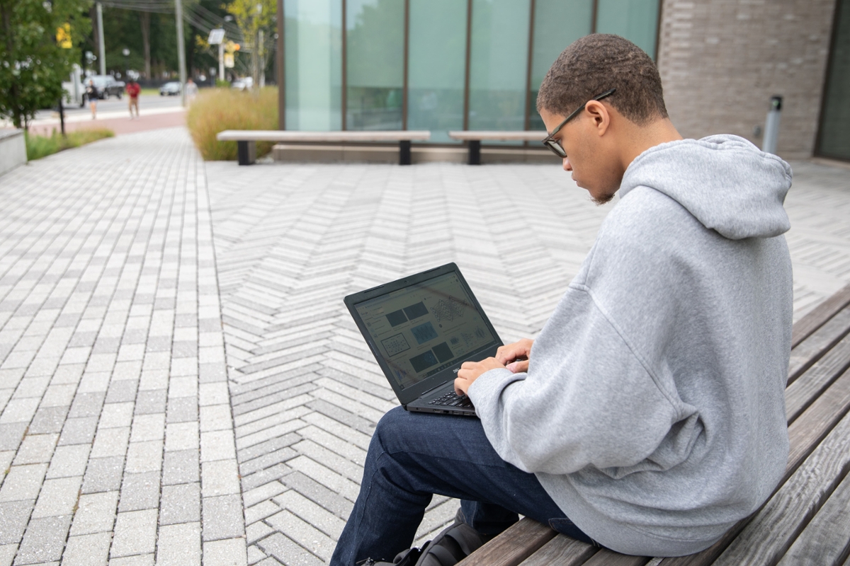 A student sits while working on their laptop.