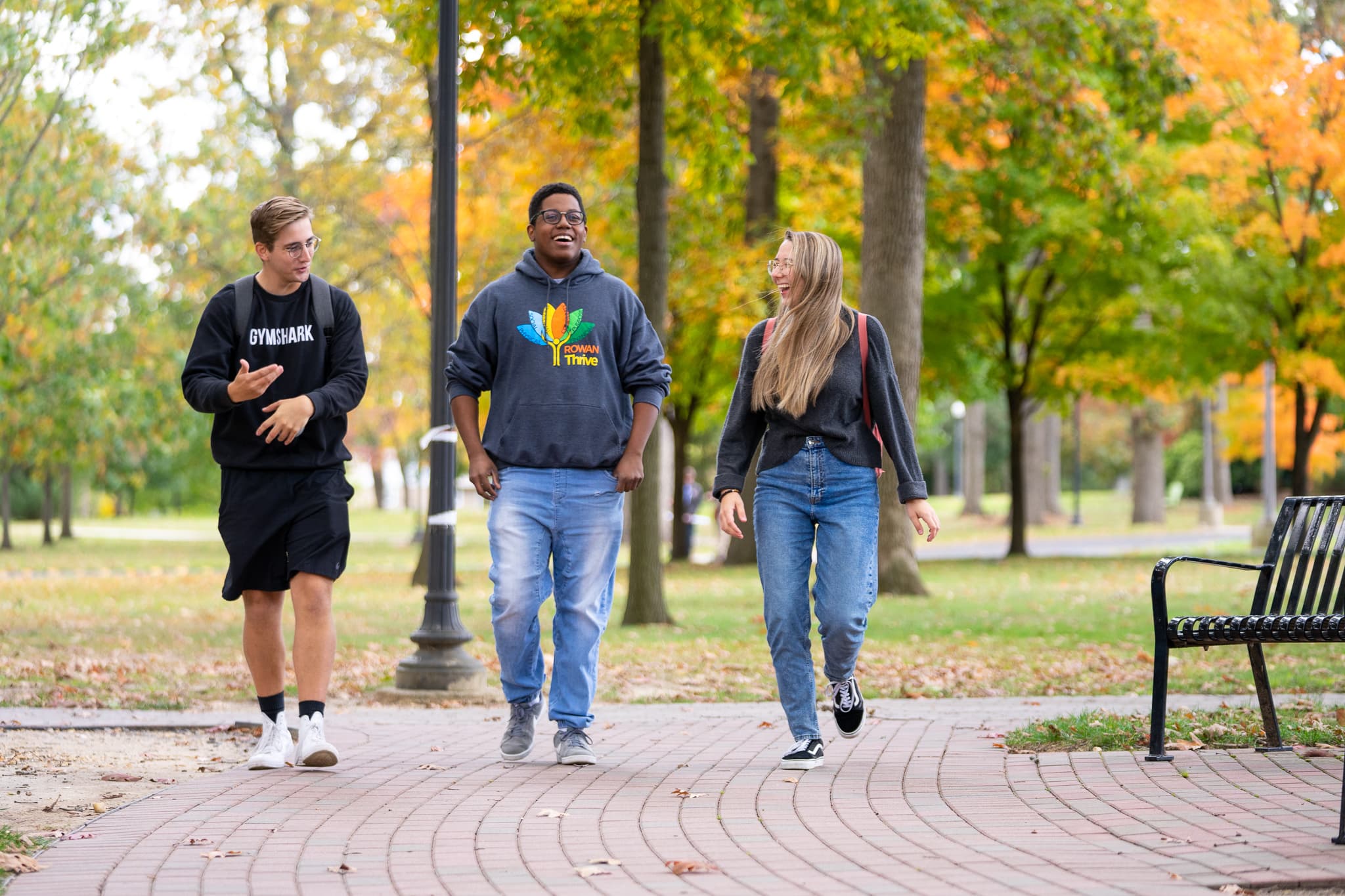 Three Rowan students walk down a sidewalk on Rowan's main campus in Glassboro, NJ.