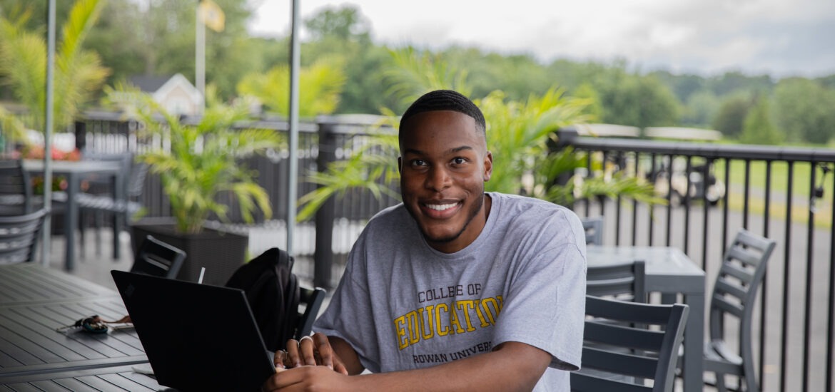 A Rowan student smiles in a College of Education t-shirt.