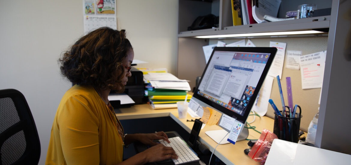 A student sits at their desk with their computer.