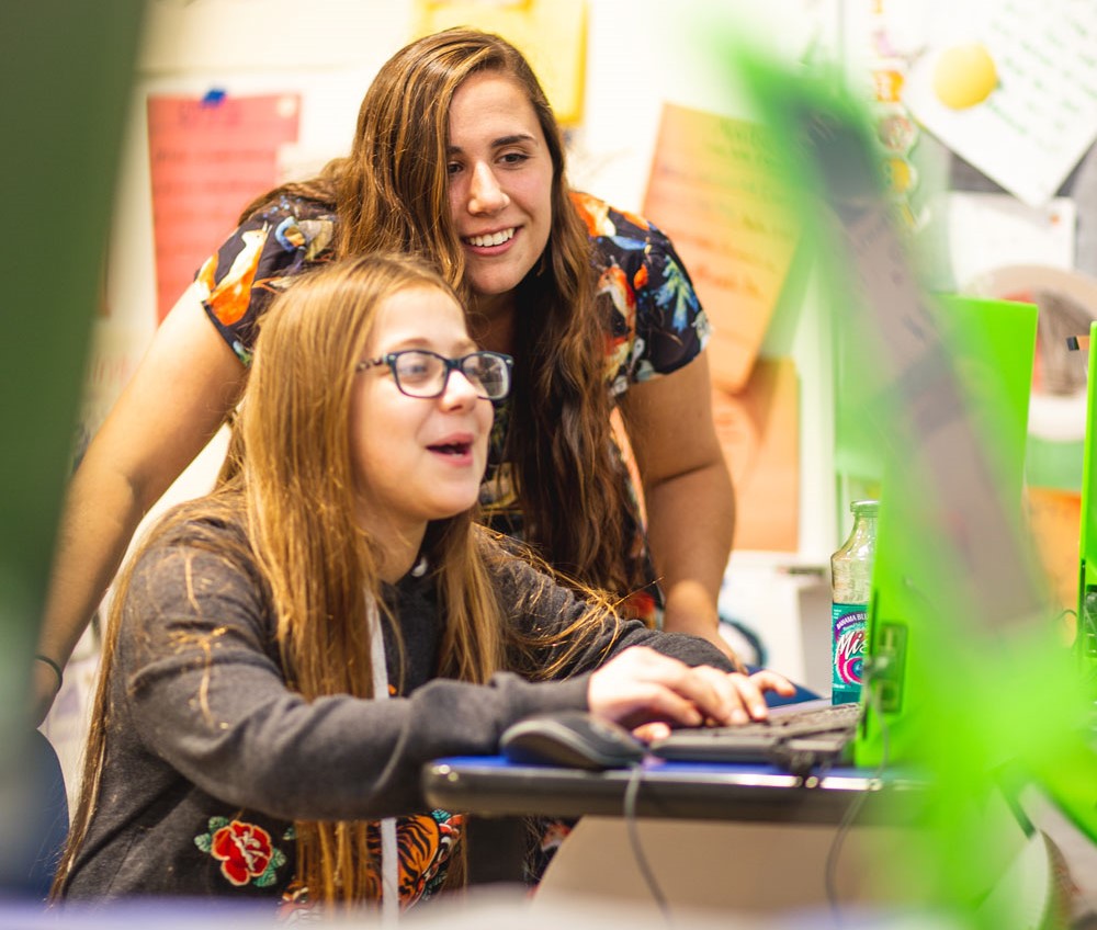 A Rowan student helps a student on the computer.