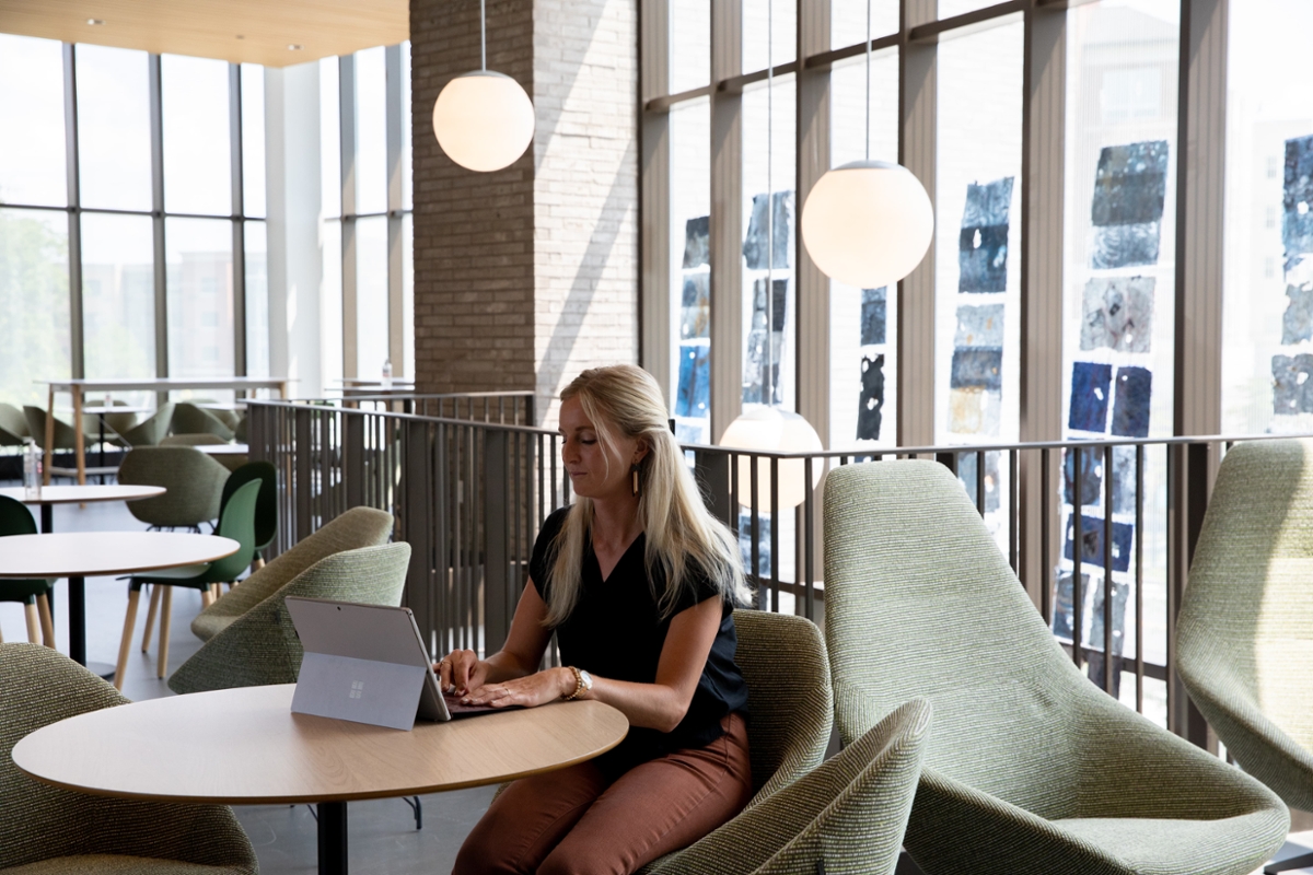 A girl sits at a table on her laptop.
