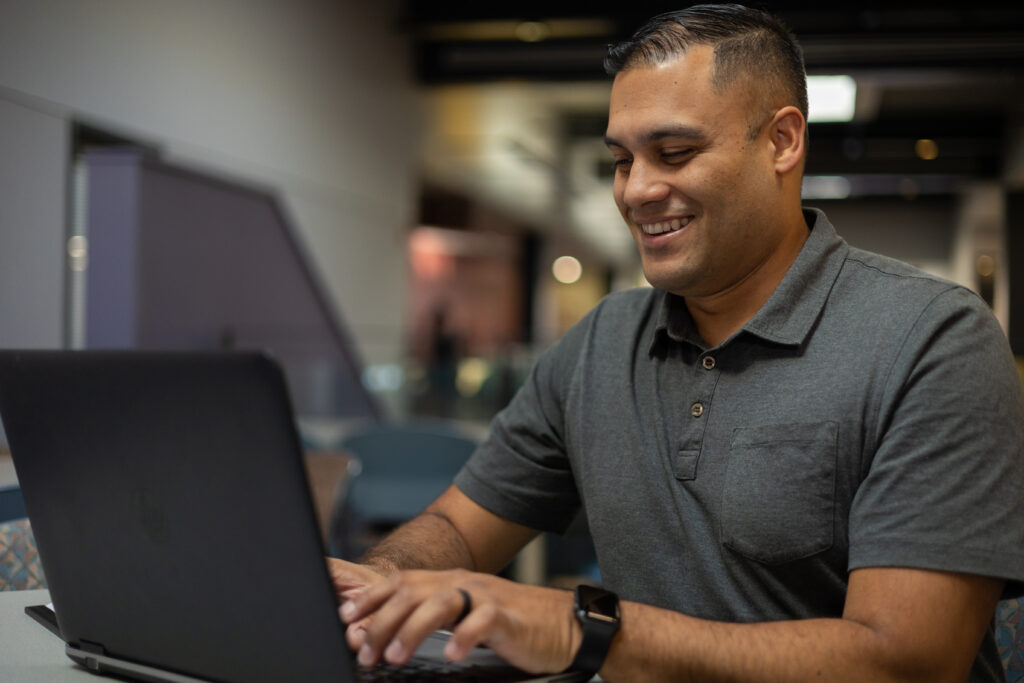 A student smiles while looking at his computer.