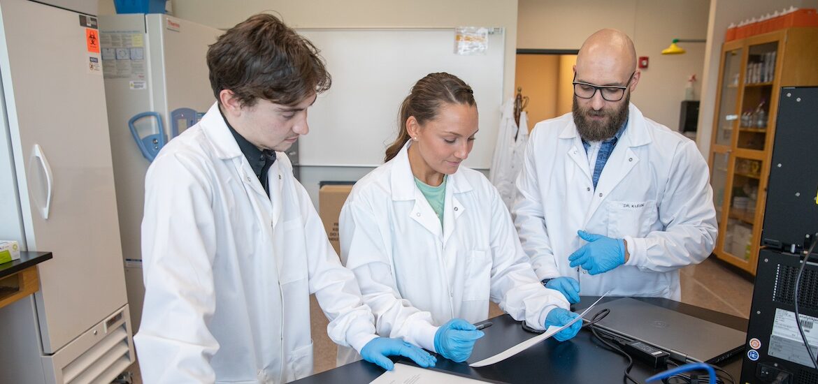 Two nursing students working with their professor.