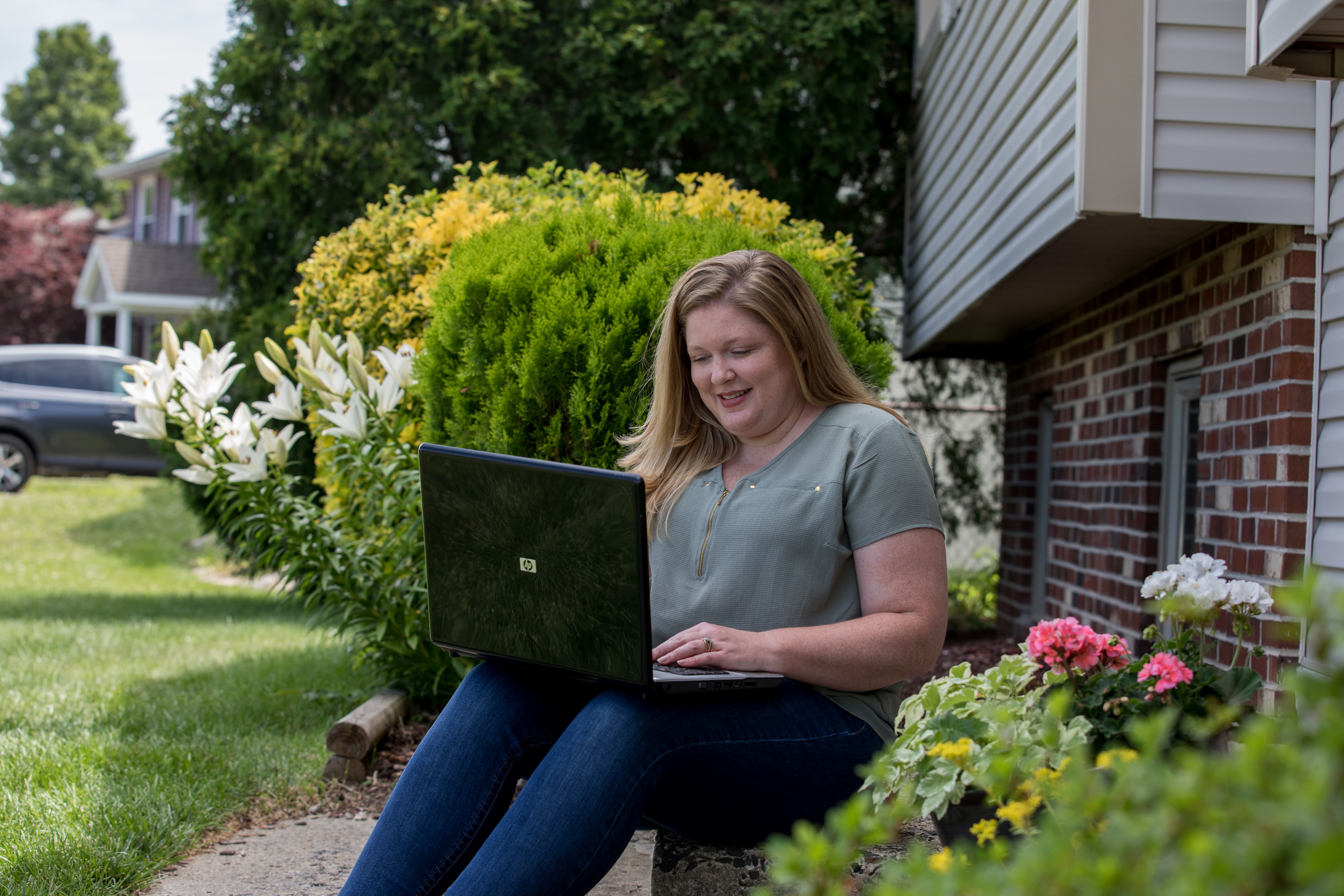 A student works outside on their laptop.