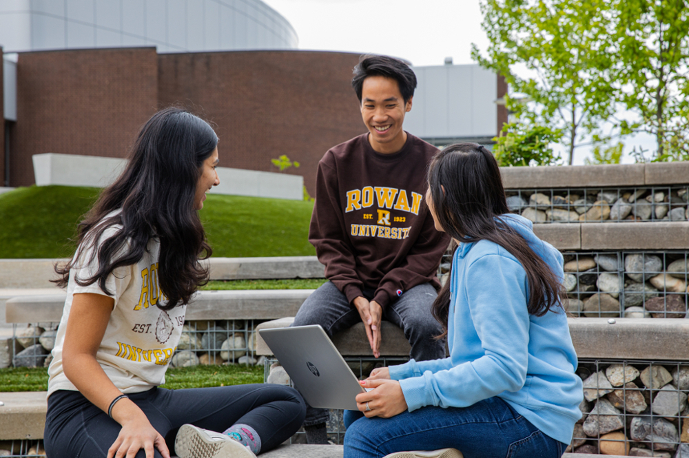 Three students smiling and talking on Rowan University's main campus in Glassboro, New Jersey.