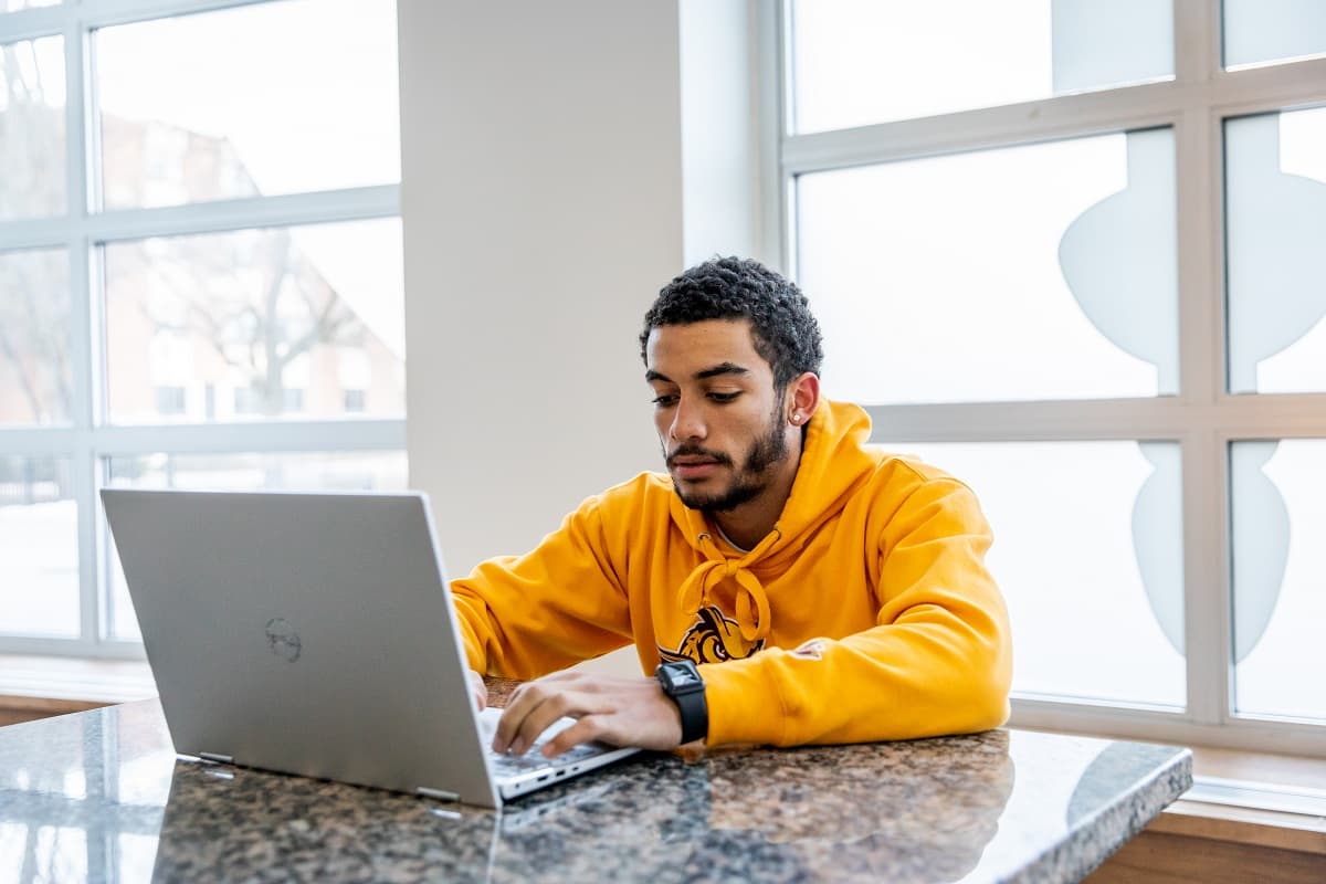 Rowan student sitting at table looking at laptop.